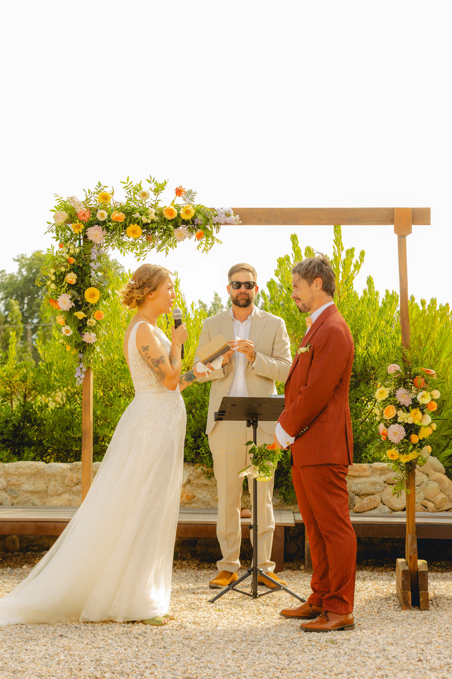 Cérémonie de mariage sous une arche fleurie, échange des vœux